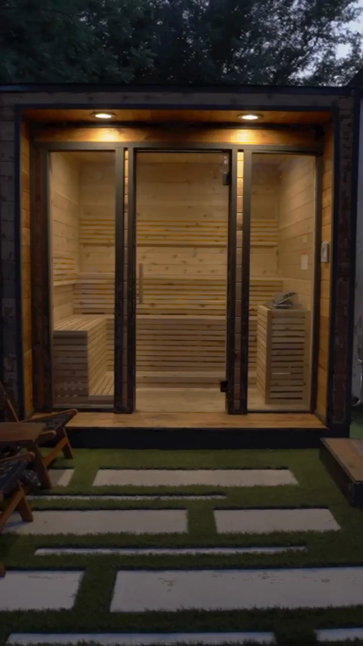 Backyard cedar sauna with glass front on artificial turf at golden hour