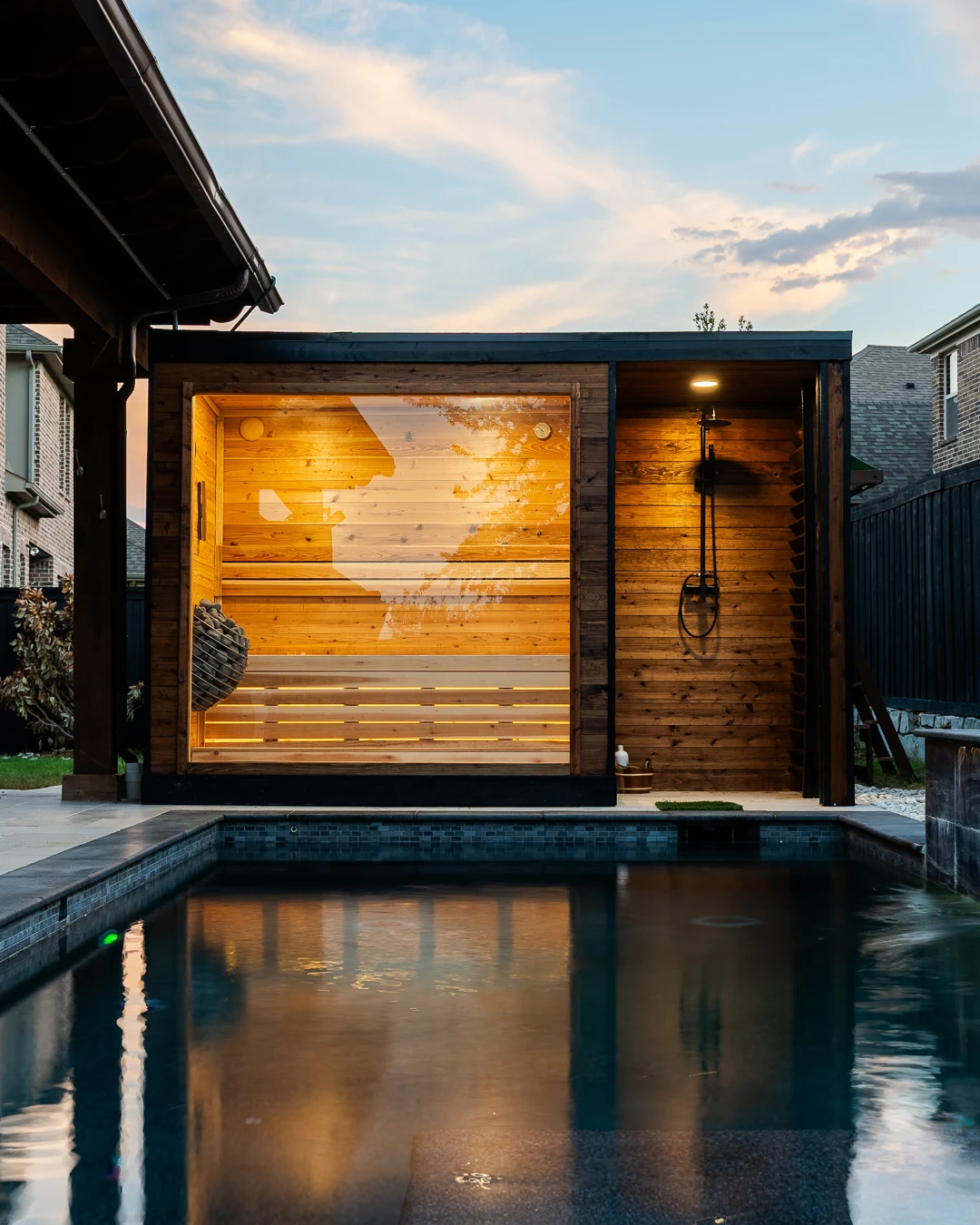 Glowing cedar sauna interior seen across the swimming pool